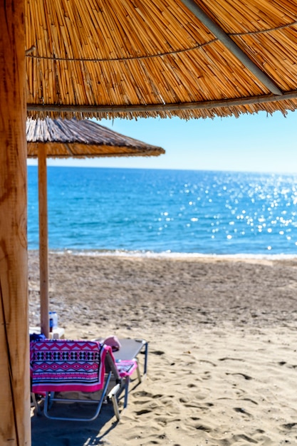 Schilfschirme und Sonnenliegen am leeren Strand