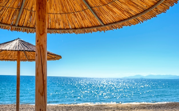 Schilfschirme und Sonnenliegen am leeren Strand