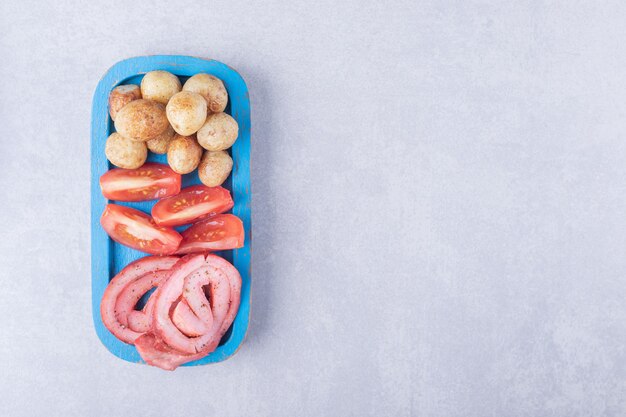 Schinkenröllchen, Tomaten und Bratkartoffeln auf blauem Teller.