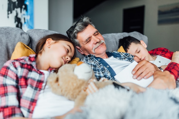 Schlafenszeit. Opa mit seinem Enkelkind, das auf dem Bett schläft, nach Märchen. Familienkonzept.