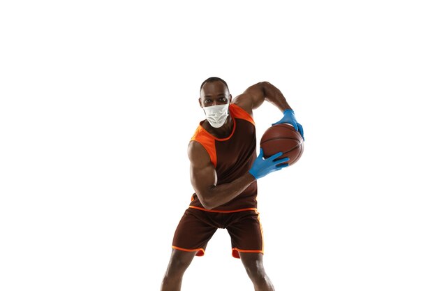 Schlag es ab. Afroamerikanischer Basketballspieler in Schutzmaske. Auch während der Quarantäne aktiv. Gesundheitswesen, Medizin, Sportkonzept.