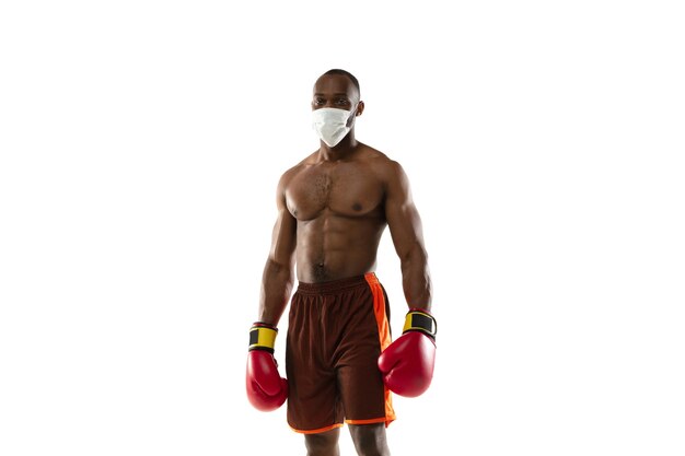 Schlagen Sie das Virus ab. Afroamerikanischer Boxer in Schutzmaske, Handschuhen.