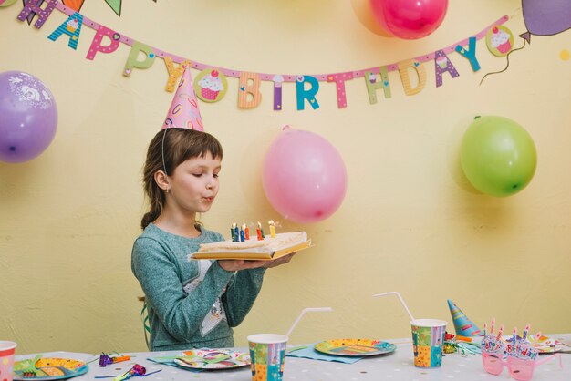 Schlagkerzen des netten Mädchens auf Kuchen