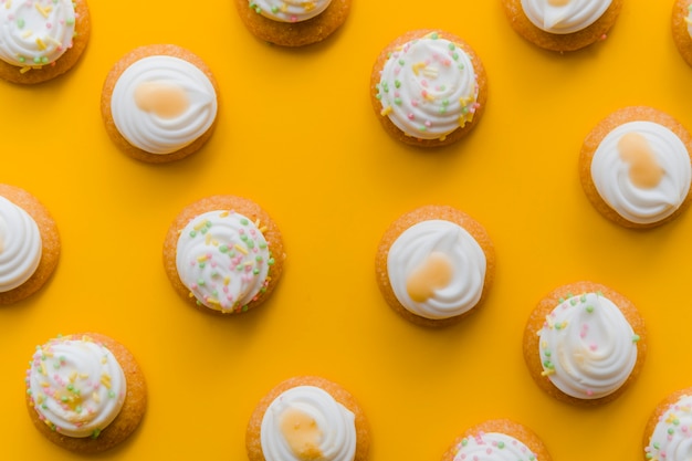 Schlagsahne über kleinem Kuchen auf einem gelben Hintergrund