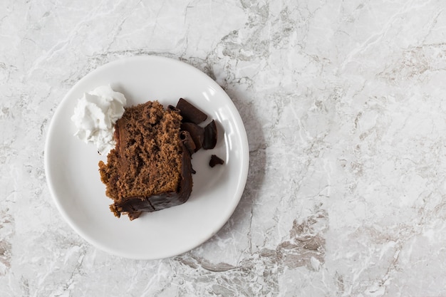 Schlagsahne und ein Stück Kuchen auf einem Teller über der Marmorplatte