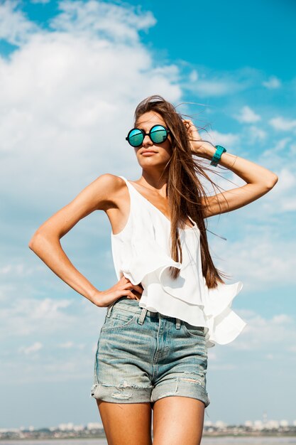 Schlanke Frau im weißen T-Shirt, das nahe Strand aufwirft.