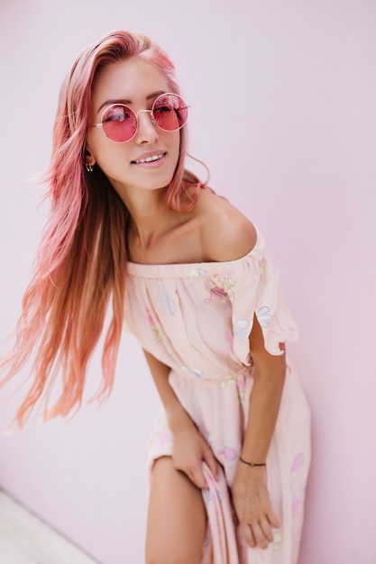 Schlanke schöne Frau mit langen rosa Haaren mit sanftem Lächeln.