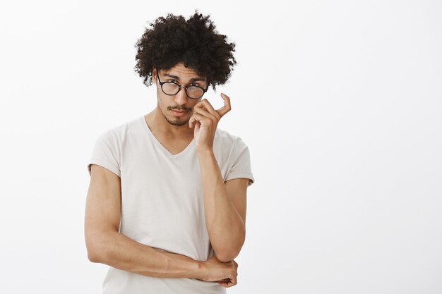 Schlauer hübscher männlicher Programmierer, der neugierig schaut und Brille trägt