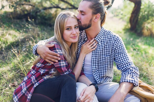 Schließen Sie das Porträt eines romantischen Paares, das sich im Park umarmt und sitzt und ein kariertes Hemd trägt.