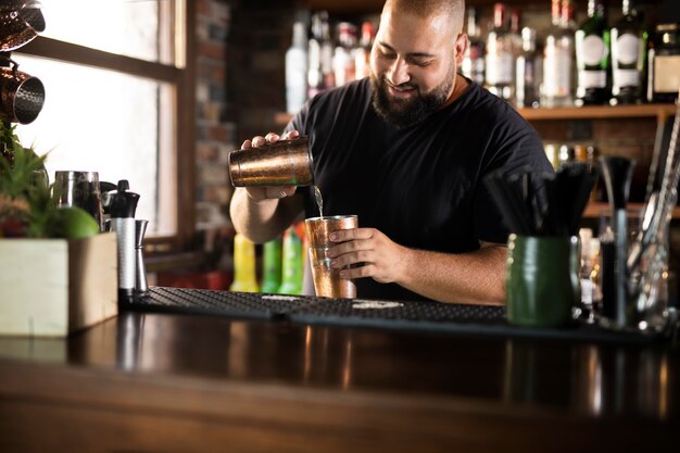 Schließen Sie den Barkeeper, der ein köstliches Getränk kreiert