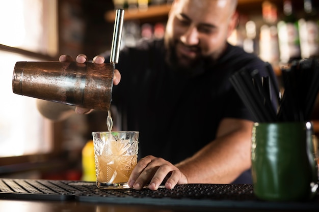 Schließen Sie den Barkeeper, der ein köstliches Getränk kreiert