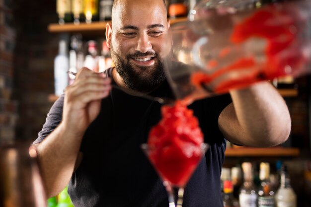 Schließen Sie den Barkeeper, der ein köstliches Getränk kreiert