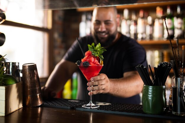 Schließen Sie den Barkeeper, der ein köstliches Getränk kreiert