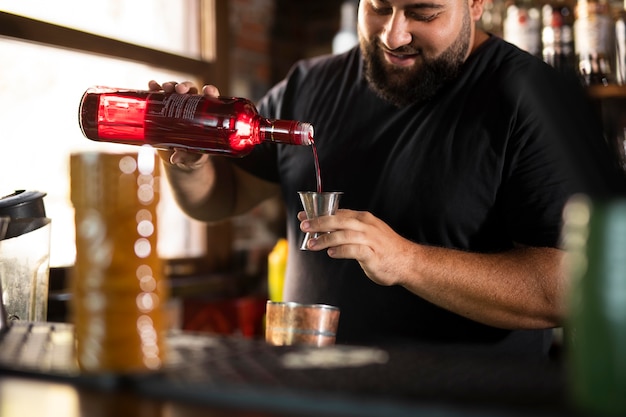 Schließen Sie den Barkeeper, der ein köstliches Getränk kreiert