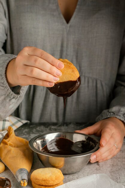 Schließen Sie die Hände, die Alfajores mit Schokolade vorbereiten