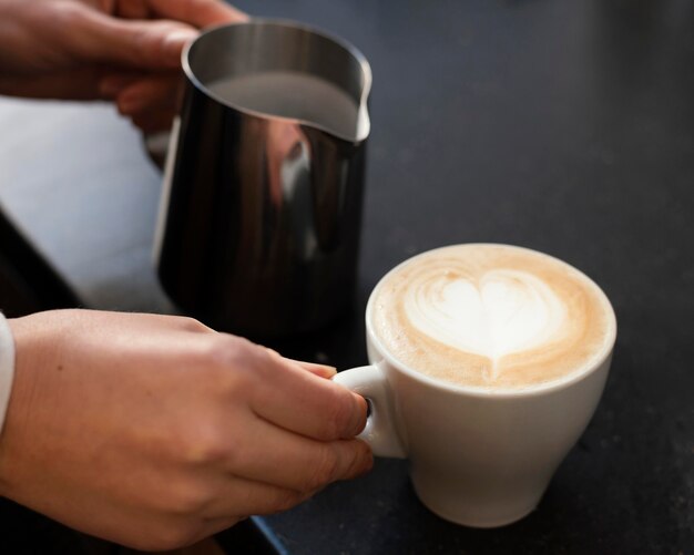 Schließen Sie die Hand, die Tasse mit Kaffee hält