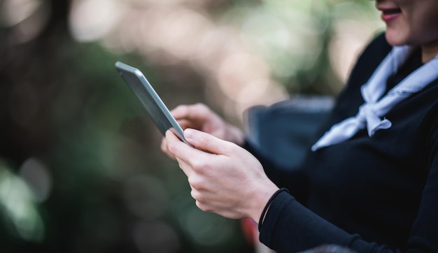 Schließen Sie die Hand einer jungen hübschen Frau, die auf einem Stuhl sitzt, und verwenden Sie ein Tablet mit glücklichem, während Sie im Naturpark-Kopienraum campen