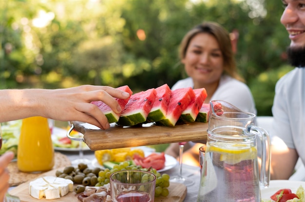 Schließen Sie Freunde am Tisch mit Wassermelone