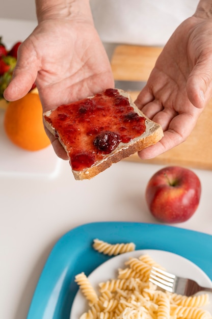 Schließen Sie Hände, die Brotscheibe mit Marmelade halten