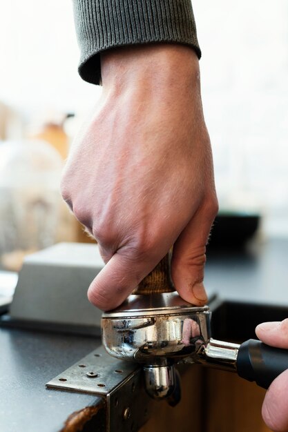 Schließen Sie Hände, die Kaffeezubereitungsgegenstand halten