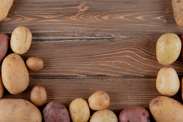 Schließen Sie herauf Ansicht der ganzen Kartoffeln auf hölzernem Hintergrund mit Kopienraum