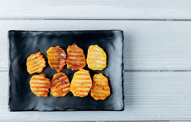 Schließen Sie herauf Ansicht der Platte mit Kartoffelchips auf hölzernem Hintergrund mit Kopienraum