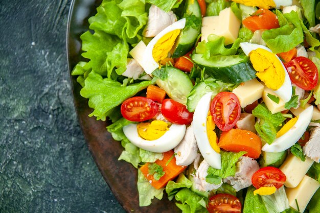 Schließen Sie herauf Ansicht des hausgemachten köstlichen Salats in einem schwarzen Teller auf der linken Seite auf grünem schwarzem Mischfarbenhintergrund mit freiem Raum