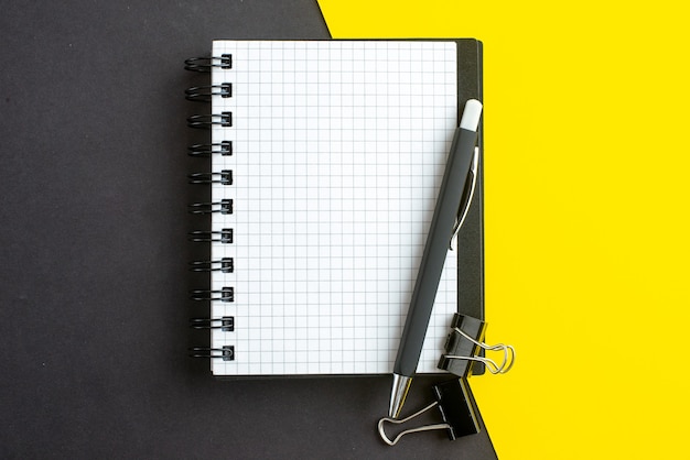 Schließen Sie herauf Ansicht des spiralförmigen Notizbuchs auf Buch und Stifte auf schwarzem gelbem Hintergrund mit freiem Raum