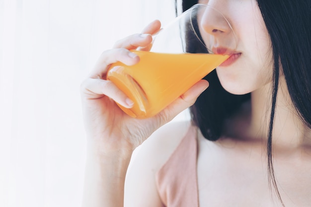 Schließen Sie herauf asiatisches nettes Mädchengefühl der Schönheitsfrau, das glücklich ist, Orangensaft für gute Gesundheit morgens zu trinken