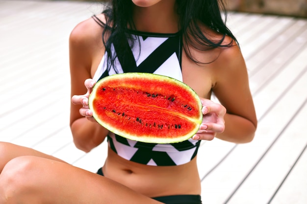 Kostenloses Foto schließen sie herauf bild der gebräunten frau, die die hälfte der wassermelone, körper positiv, gesunde vegane fruchternährung und lebensstil hält.
