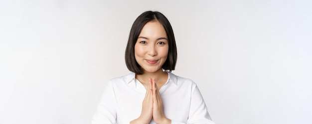 Schließen sie herauf das porträt der jungen japanischen frau, die namaste zeigt, danke arigatou-geste, die über weißem hintergrund steht