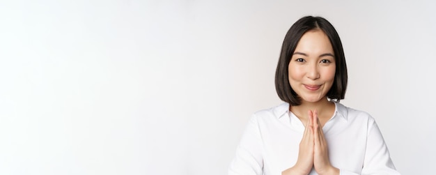 Schließen sie herauf das porträt der jungen japanischen frau, die namaste zeigt, danke arigatou-geste, die über weißem hintergrund steht