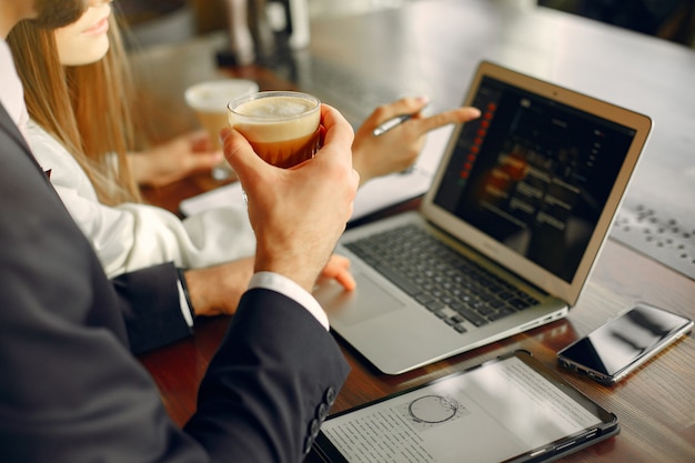 Schließen Sie herauf den Mann, der mit einem Laptop am Tisch arbeitet