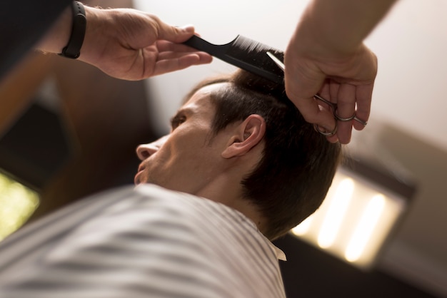 Schließen Sie herauf den Mann der niedrigen Ansicht, der einen Haarschnitt erhält