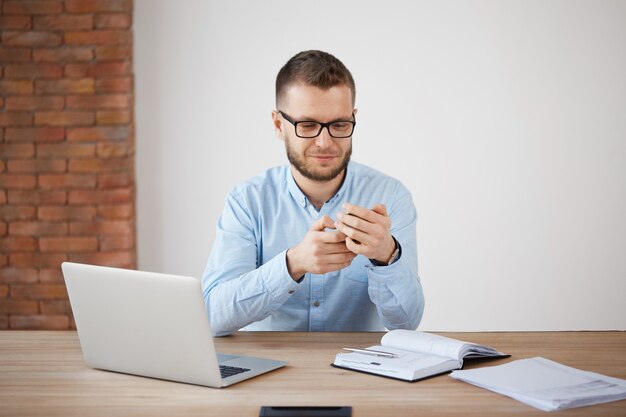 Schließen Sie herauf des reifen unrasierten Mannes in den Gläsern und im Hemd bei der Arbeit, Chat mit Frau durch Smartphone während des Mittagessens.