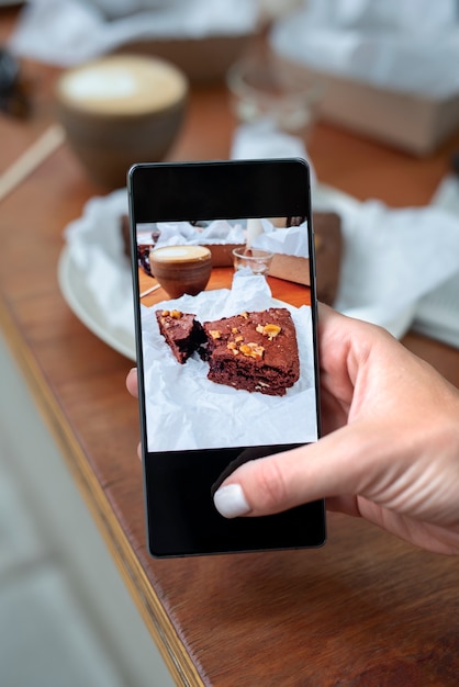 Schließen Sie herauf die Hände, die Kuchenstückfotos machen