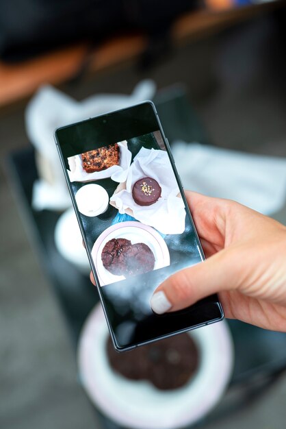 Schließen Sie herauf die Hand, die Kuchenfotos hält