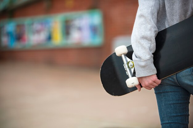 Schließen Sie herauf die Hand, die Skateboard hält