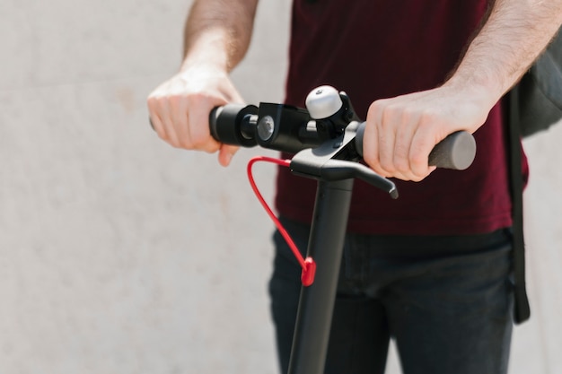 Schließen Sie herauf E-Roller-Mitfahrer mit defocused Hintergrund