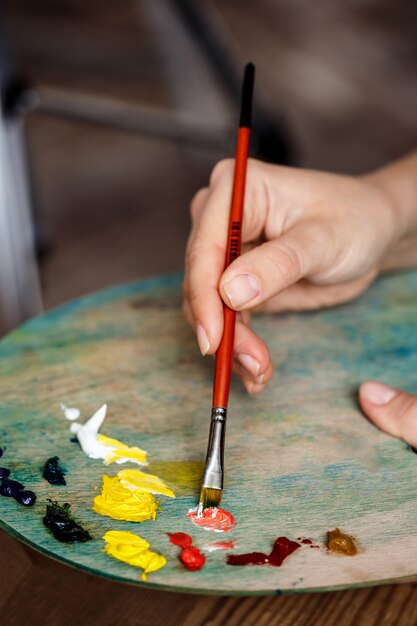 Schließen Sie herauf Foto der Frau, die Ölfarben auf Palette mischt