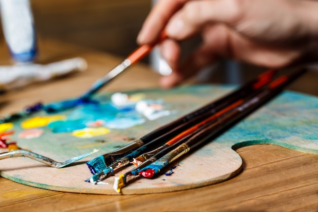 Schließen Sie herauf Foto der Frau, die Ölfarben auf Palette mischt