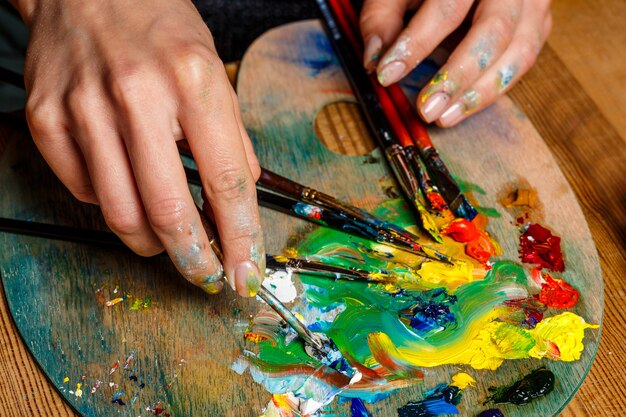 Schließen Sie herauf Foto der Frau, die Ölfarben auf Palette mischt