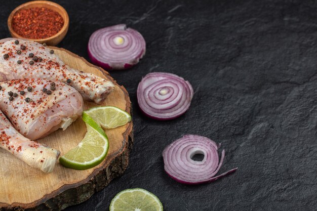 Schließen Sie herauf Foto des rohen Huhns mit Zwiebel und Limette.