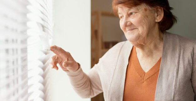 Schließen Sie herauf Frau, die aus dem Fenster schaut