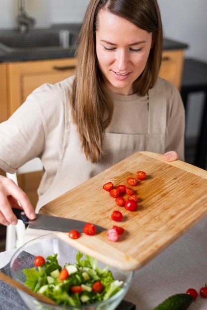 Schließen Sie herauf Frau, die Tomaten in Salat setzt