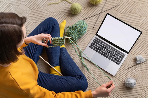 Schließen Sie herauf Frau mit dem Stricken des Laptops