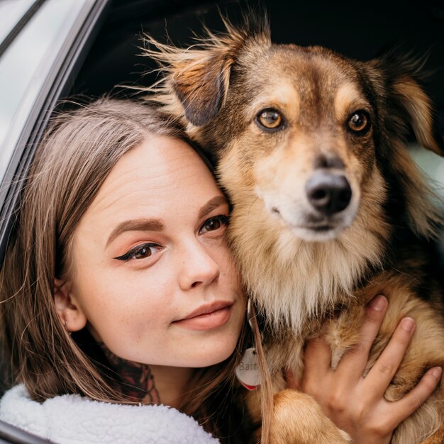 Schließen Sie herauf Frau und Hund, die durch Autofenster schauen