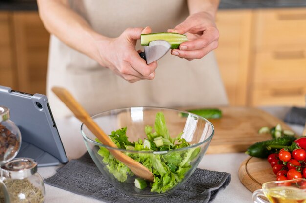 Schließen Sie herauf Hände, die Gurke in der Küche schneiden