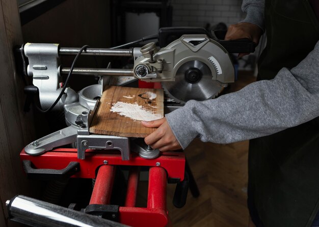 Schließen Sie herauf Hände, die Holz schneiden