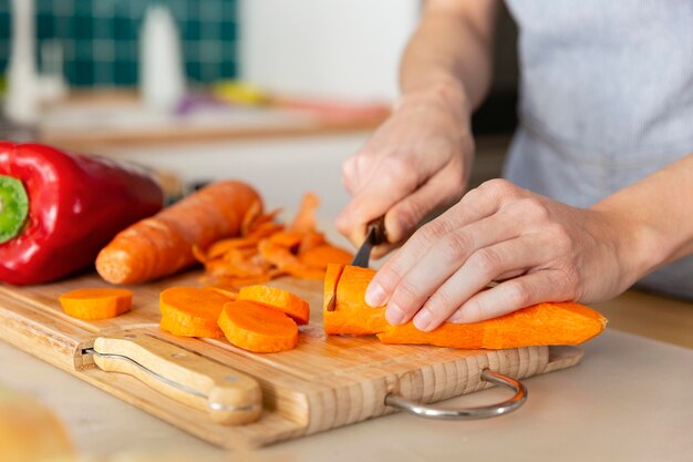 Schließen Sie herauf Hände, die Karotte schneiden